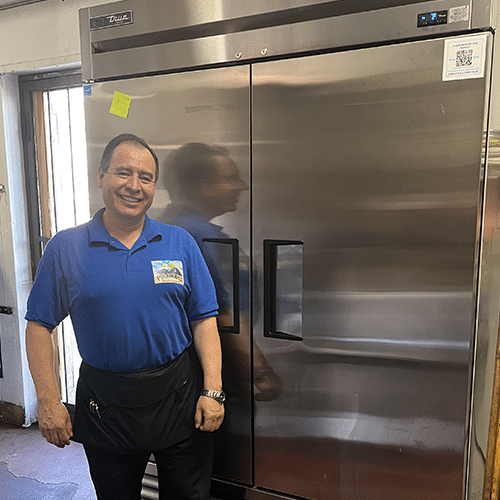  Piramides owner pictured with their new efficient refrigeration equipment. Piramides Mexican Restaurant upgraded a freezer with an Energy Star unit, and installed indoor LED lights and a sensor. This project was awarded $5,364 in funding.